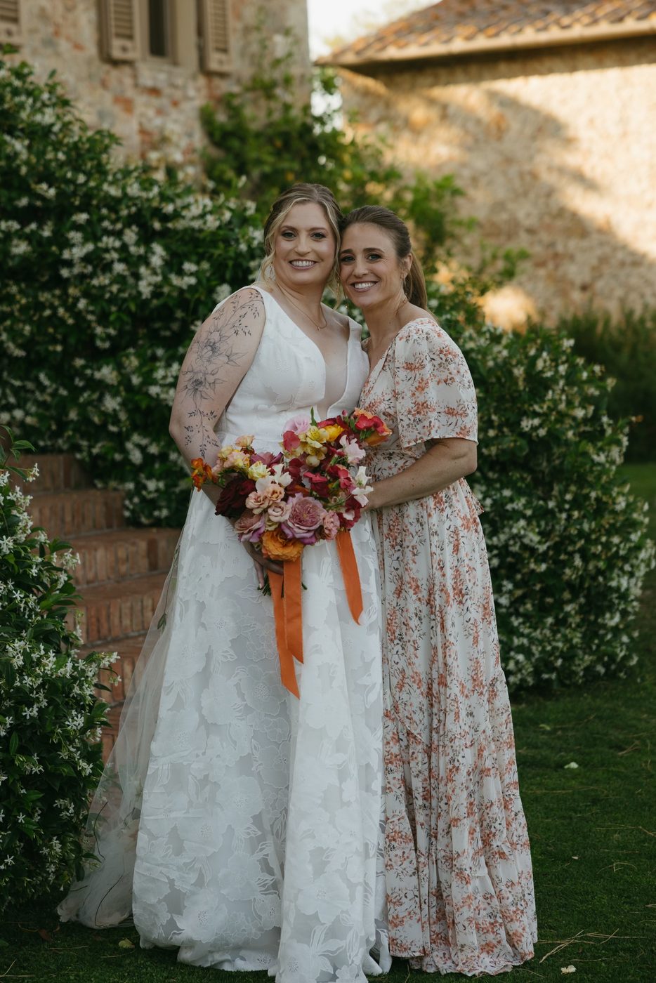 Jess Mansell embracing a bride at a wedding in the Tuscan countryside.